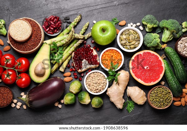 Fresh vegetables, fruits and seeds on black table,\
flat lay