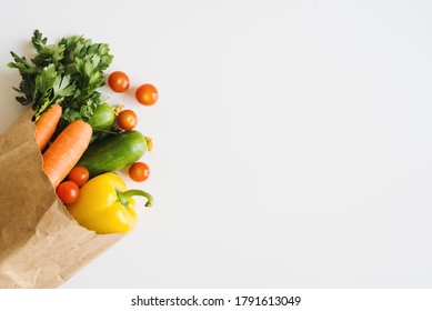 Fresh Vegetables And Herbs In Eco Friendly Paper Bag On White Background, Top View. Food Delivery. Grocery Shopping