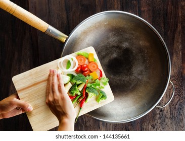 Fresh vegetables on the cutting board are falling in the wok. Concept of cooking. - Powered by Shutterstock