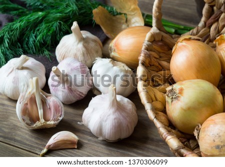 Fresh vegetables on a wooden table - garlic, onion in the basket and dill.
