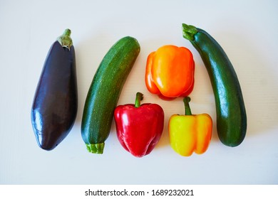 Fresh vegetables prepared for cooking on kitchen table. Ripe organic eggplant, bell pepper and zucchini on white background