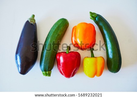 Fresh vegetables prepared for cooking on kitchen table. Ripe organic eggplant, bell pepper and zucchini on white background