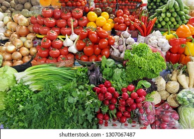 fresh vegetables tomatoes, onions,greens, parsley, dill, salad, onion, radish, chili and garlic on a market place colorful