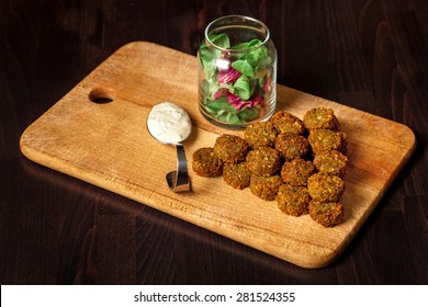 falafel végétal frais avec sauce et herbes fraîches sur un tableau en bois : photo de stock