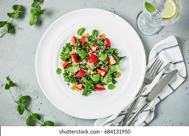 Fresh Vegetarian Salad With Kale, Strawberries, Quinoa And Mint Leaves. White Plate From Above (top View, Flat Lay). Grey Stone Background.