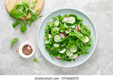 Fresh vegetarian vegetable salad with radish, cucumber and arugula, healthy food, top view.