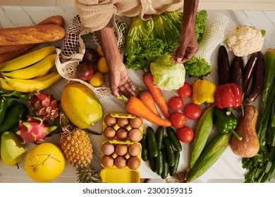 Fresh veggies, fruits, eggs and bread on kitchen table in front of Black woman - Powered by Shutterstock