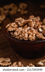 Fresh walnut kernels in a brown bowl on a rustic wooden background. Walnut kernels close up.
