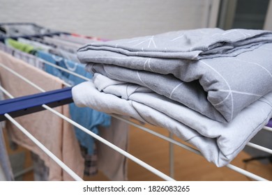 Fresh Washed Bed Linen Stacked, Piled On A Dryer, Dry Apparel On A Folding Portable Dryer Close Up, Housekeeping, Homework And Chores Concept.