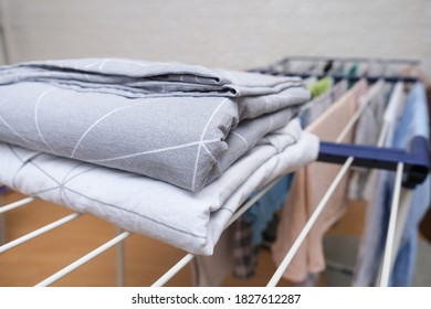 Fresh Washed Bed Linen Stacked, Piled On A Dryer, Dry Apparel On A Folding Portable Dryer Close Up, Housekeeping, Homework And Chores Concept.