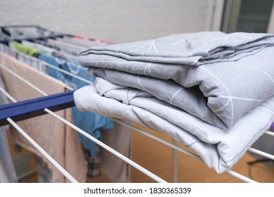 Fresh Washed Bed Linen Stacked, Piled On A Dryer, Dry Apparel On A Folding Portable Dryer Close Up, Housekeeping, Homework And Chores Concept.