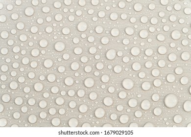 Fresh Water Drops On A Gray Glossy Surface Close-up. Waterproofing Stain Dye Coating For Construction. Abstract Background.