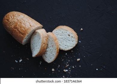 Fresh wheat sliced bread and crumbs on dark background