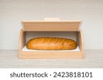 Fresh white bread in opened wooden bread box on table top at home kitchen. Closeup. Front view.