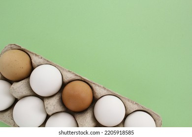 Fresh White And Brown Chicken Eggs In Carton Paper Box On Green Background. Natural Healthy Nutrition Organic Farm Food Product Concept. World Egg Day, Easter Holiday Composition. Copy Space, Flatlay