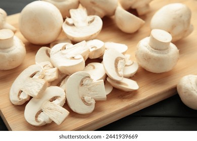 Fresh white champignon mushrooms on cutting board on black background. - Powered by Shutterstock