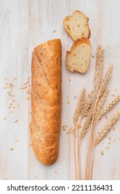 Fresh White Wheat Bread, French Baguette, Wheat Ears And Grains On White Wooden Background Top View. Bread Making, Bakery, Healthy Food. Bread Background. Light Mockup