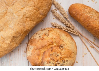 Fresh White Wheat Bread, Round Classic, Ciabatta, French Baguette, Wheat Ears And Grains On White Wooden Background Top View. Bread Making, Bakery, Healthy Food. Bread Background. Light Mockup