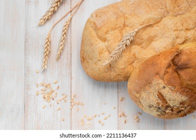 Fresh White Wheat Bread, Round Classic, Ciabatta, French Baguette, Wheat Ears And Grains On White Wooden Background Top View. Bread Making, Bakery, Healthy Food. Bread Background. Light Mockup