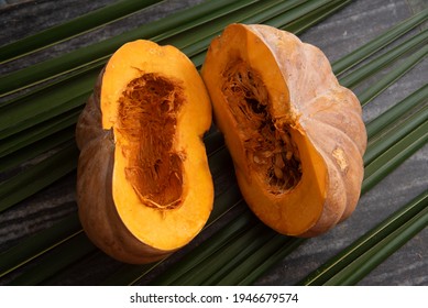 Fresh Whole Pumpkin Vegetable Cut In Half , Large Raw Ripe Orange Pumpkin Sliced Isolated On Palm Leaves. Winter Squash From Farm Harvested In Kerala India