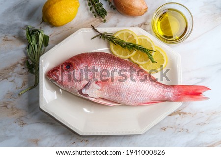 Fresh whole raw head-on red snapper with seasoning ingredients