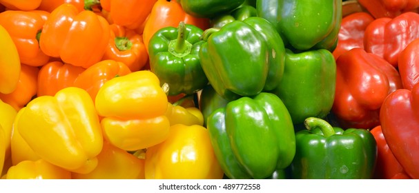 Fresh yellow, orange, green and red organic bell peppers capsicum on display for sale at local farmer's market departmental store.