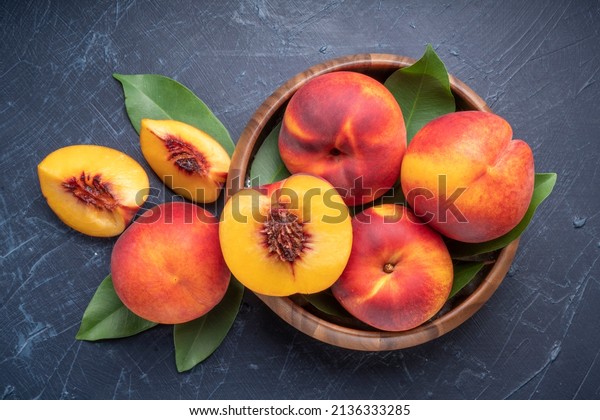 Fresh Yellow Peach\
fruit in wooden bowl on wooden background, Yellow Peach with slice\
in wooden basket.