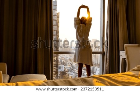 Fresh of young woman open a curtains and stretching in bed after waking up, sunlight in morning