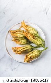 Fresh zucchini flowers (Fiori di zucca) for frying on a white marble background. Interesting South Italian Cuisine Ingredients