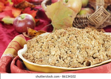 Freshly Baked Apple Crisp With Fresh Apples And Autumn Leaves In The Background. Shallow Depth Of Field With Selective Focus On The Foreground.