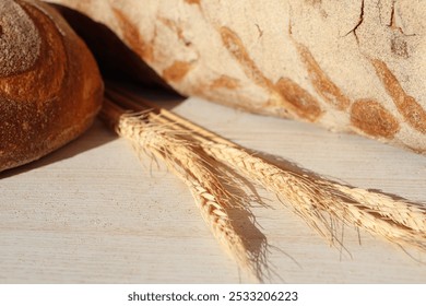 Freshly Baked Artisan Bread Displayed Alongside Beautiful Golden Wheat Stalks on a Rustic Surface - Powered by Shutterstock