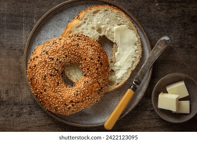 freshly baked bagel with butter, healthy breafast concept, wooden background, top view - Powered by Shutterstock