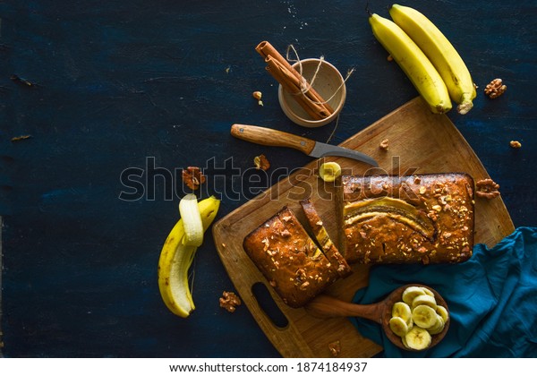 Freshly baked banana bread, sliced on a cutting\
board, with banana, cinnamon and nuts. bakery, cake, home chef,\
hotel, menu concepts.