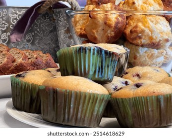 Freshly baked blueberry muffins, cheese scones and banana bread are laid out on a table in preparation for a brunch celebration - Powered by Shutterstock