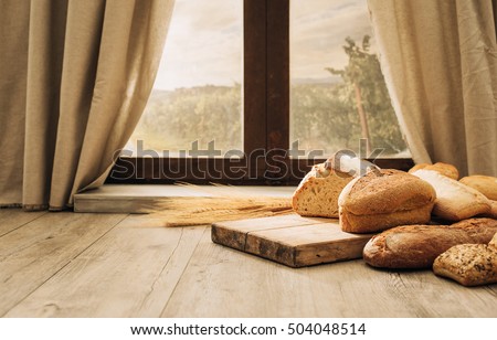 Freshly baked bread on a chopping board on the kitchen table in front of a window, healthy eating concept