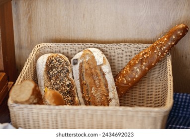 Freshly baked breads placed inside a woven basket. The breads have different shapes and toppings, bakery items, whole grain, adorned with various seeds and herbs on its crust. Rustic brown bread - Powered by Shutterstock