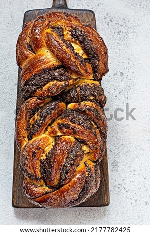 Freshly baked briocheBabka with poppy seeds and chocolate on a wooden board. Braided dessert bread. Homemade baking, national pastries. Estonian kringle in the shape of a brick.