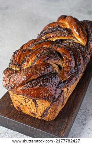 Freshly baked briocheBabka with poppy seeds and chocolate on a wooden board. Braided dessert bread. Homemade baking, national pastries. Estonian kringle in the shape of a brick.