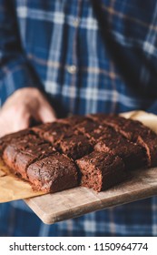 Freshly Baked Brownies On Wooden Serving Board. Hands Holding Tray With Brownies