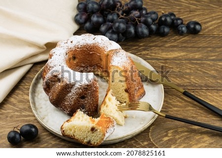 freshly baked cake on a ceramic plate on a wooden table with a bunch of wine
