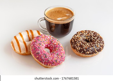 freshly baked chocolate, caramel and strawberry donuts and a cup of coffee on a white glass surface - Powered by Shutterstock