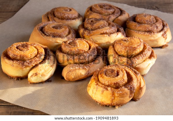Freshly baked cinnamon buns with\
spices and cocoa filling on parchment paper. Sweet Homemade Pastry\
christmas baking. Close-up. Kanelbule - swedish\
dessert.