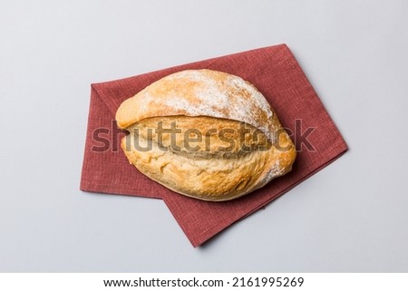 Freshly baked delicious french bread with napkin on rustic table top view. Healthy white bread loaf.