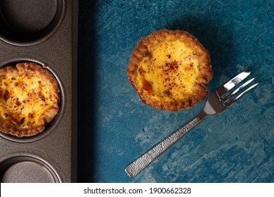 A Freshly Baked Egg Custard Tart From Above With A Cake Fork Laid To The Side And A Baking Tray Containing Another Tart