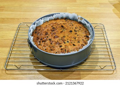 Freshly Baked Fruit Cake In A Baking Tin Standing On A Wire Cooling Rack. No People.