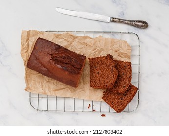 Freshly baked homemade banana chocolate loaf. Pound cake with chocolate pieces in close-up. Dessert slices on baking paper. Marble background. Selective focus, top view