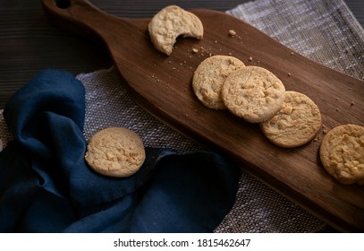 Freshly Baked Homemade Cookies, On A Wooden Board And With A Dark Blue Napkin.
