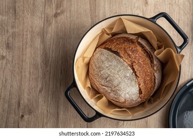 Freshly Baked Homemade Sour Dough Bread In Cast Iron Dutch Oven , Wooden Background, Top View, Copy Space