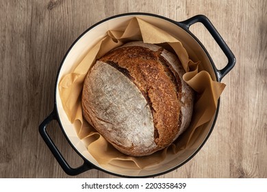 Freshly Baked Homemade Sour Dough Bread In Cast Iron  Dutch Oven , Wooden Background, Top View