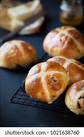 Freshly baked Hot Cross buns on a cooling rack  with butter and honey at the background